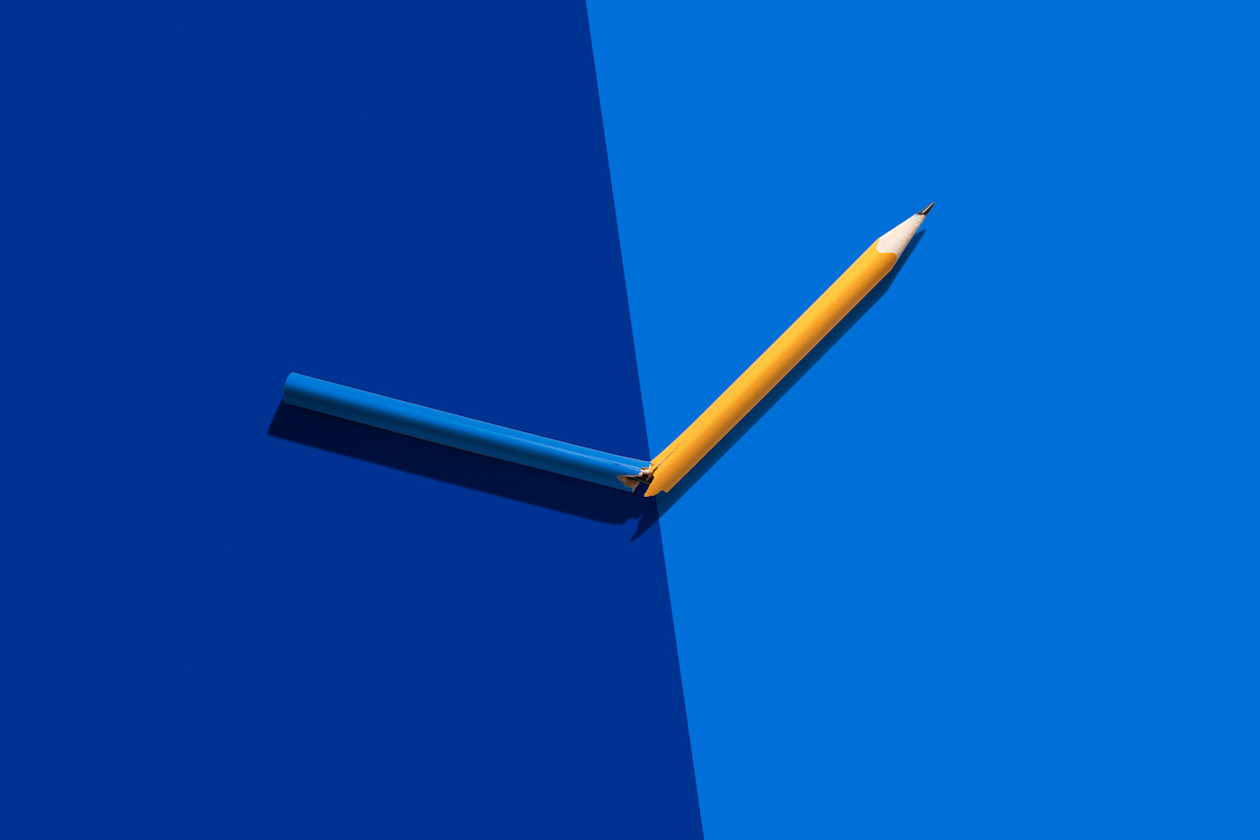 Pencil Cracked into Two Colors on Solid Color Block Background.