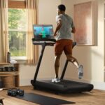 Peloton Tread, man running on the treadmill while watching workout video