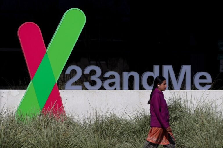 A pedestrian walks by a sign posted in front of the 23andMe headquarters in Sunnyvale, California. (Image: Justin Sullivan/Getty Images)