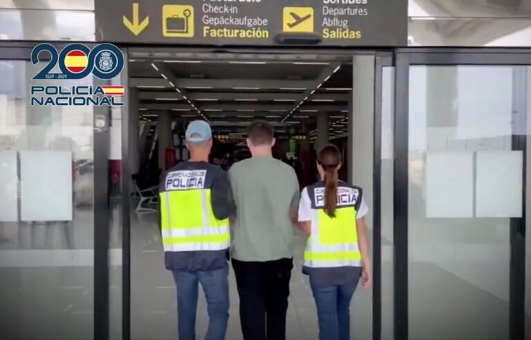 a photo of the back of two police officers leading an alleged hacking suspect into an airport