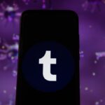Photo illustration of a Tumblr logo displayed on a smartphone with a COVID 19 sample image in the background.